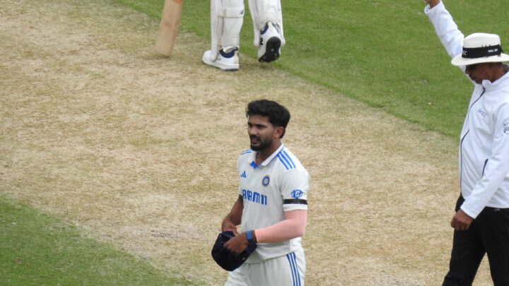 టెస్టు తెల్ల దుస్తుల్లో టోపీ చేతిలో పట్టుకుని పిచ్‌పై నడుస్తున్న నితీశ్ కుమార్ రెడ్డి, పక్కన సైగ చేస్తున్న అంపైర్.