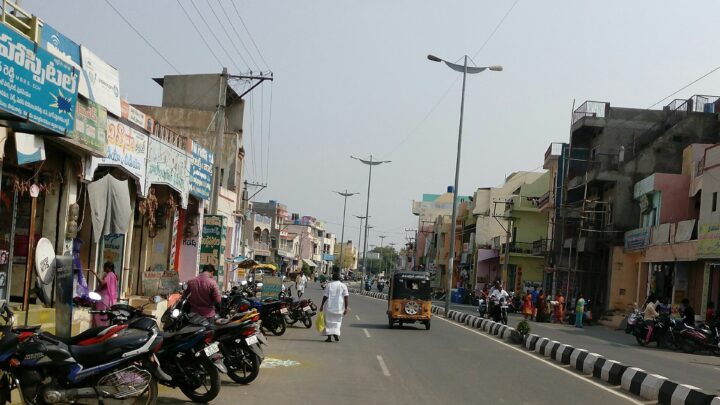దుకాణాలు, పార్క్ చేసిన ద్విచక్ర వాహనాలు, ఆటోతో పులివెందుల పట్టణంలోని ప్రధాన రహదారి.