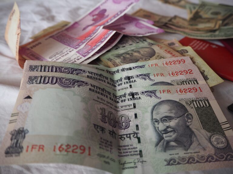 రూ.100, రూ.2,000 నోట్లు, వెనుక అమెరికా డాలర్ నోట్లు.