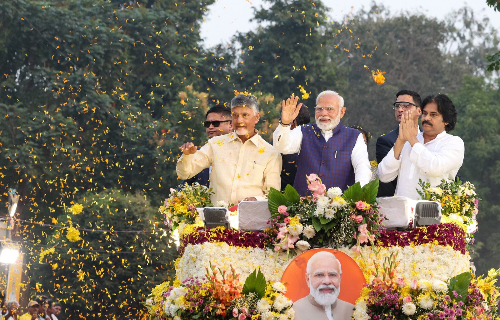 పూలతో అలంకరించిన వాహనంపై నుంచి చంద్రబాబు నాయుడు, నరేంద్ర మోదీ, పవన్ కల్యాణ్ జనానికి అభివాదం చేస్తుండగా చుట్టూ పూలవర్షం.