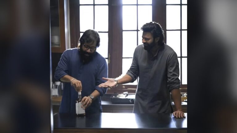 పొడవైన కిటికీలున్న వంటగదిలాంటి గదిలో ఇద్దరు వ్యక్తులు: నీలి చొక్కా, కళ్లద్దాలతో ఉన్న ఒకరు సాదా లేబుల్ ఉన్న సీసా మూత తీస్తుండగా, బూడిద రంగు కుర్తాలో ఉన్న మరొకరు నవ్వుతూ ఆయన వైపు చేయి చూపిస్తున్నారు.